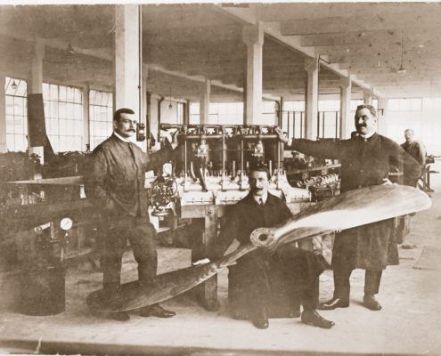 Historische Aufnahme von Ingenieuren, die an einem Flugzeugmotor arbeiten. 
