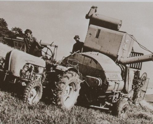 Historisches Bild der ersten Landwirtschaftstraktoren auf dem Feld bei der Arbeit