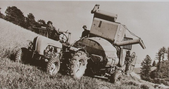 Historisches Bild der ersten Landwirtschaftstraktoren auf dem Feld bei der Arbeit