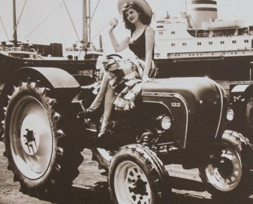 Junge Dame sitzt auf dem Porsche Traktor in einem Hafen 