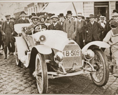 Gruppe von Männern versammelt sich um einer der ersten Rennwagen